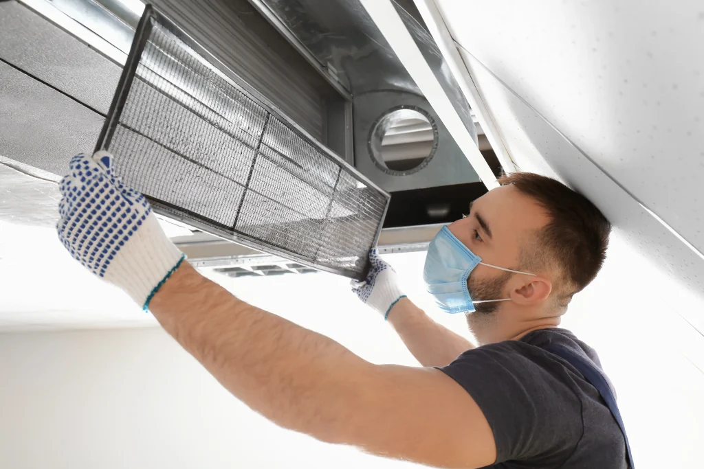 male-technician-cleaning-industrial-air-conditioner-indoors